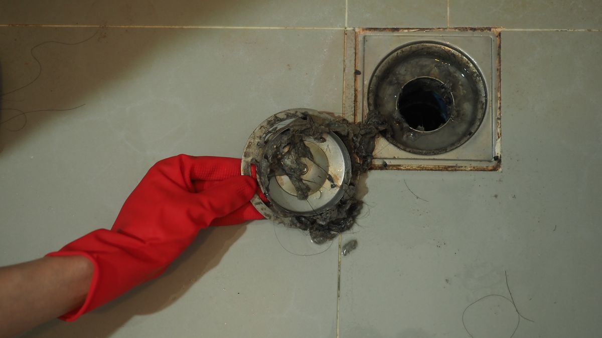 Blocked and dirty floor drain with sewer pipework exposed below