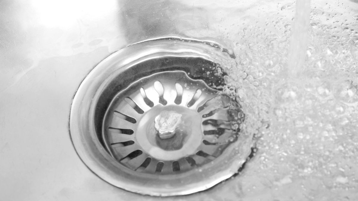 Close-up of water draining through a stainless steel kitchen sink strainer