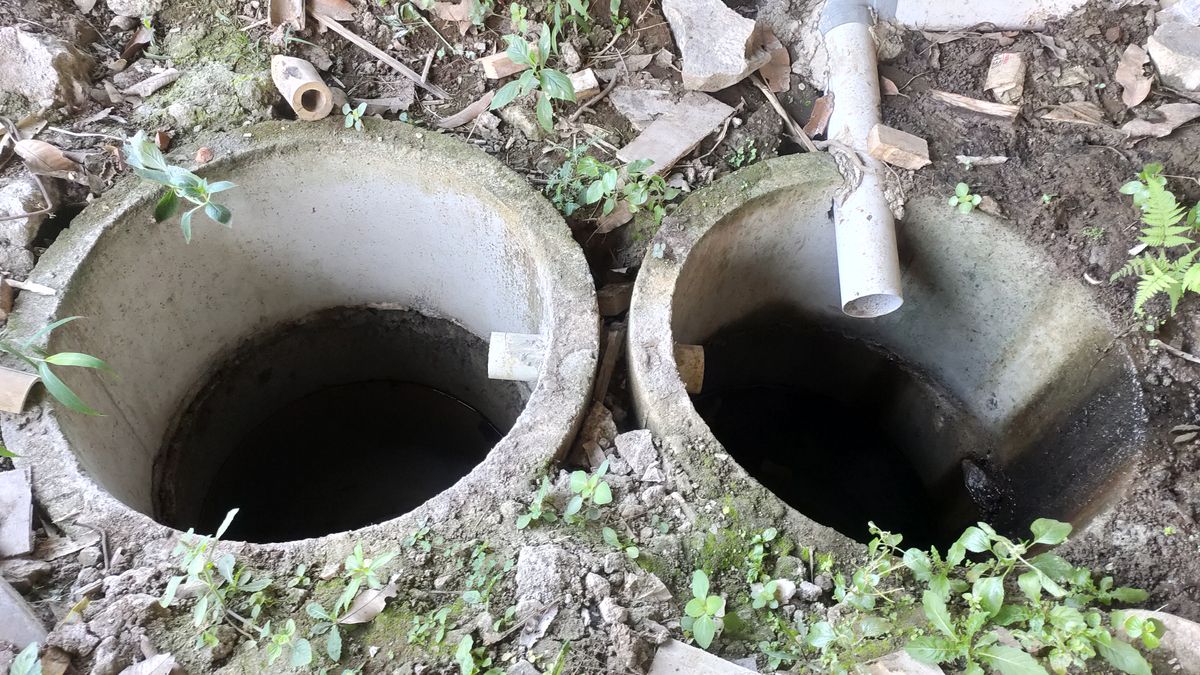 Two concrete septic chambers set in the ground with a PVC inlet pipe between them