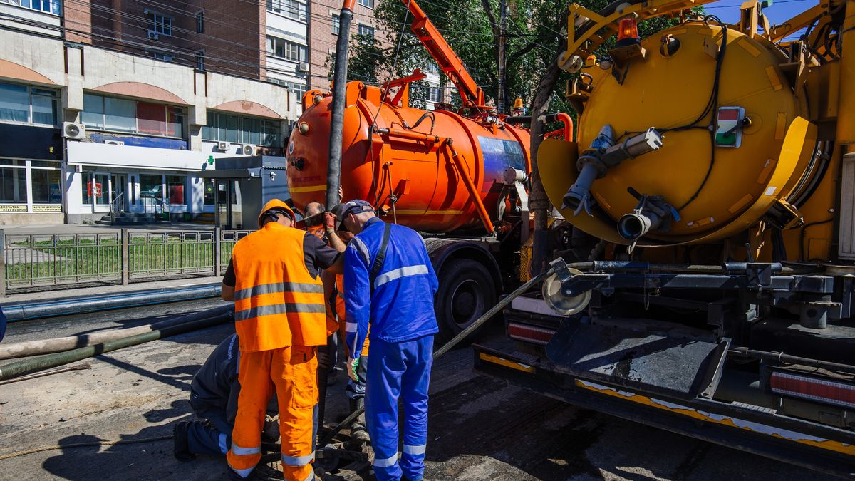 Crew operating a vacuum tanker to pump out a sewer line from the street